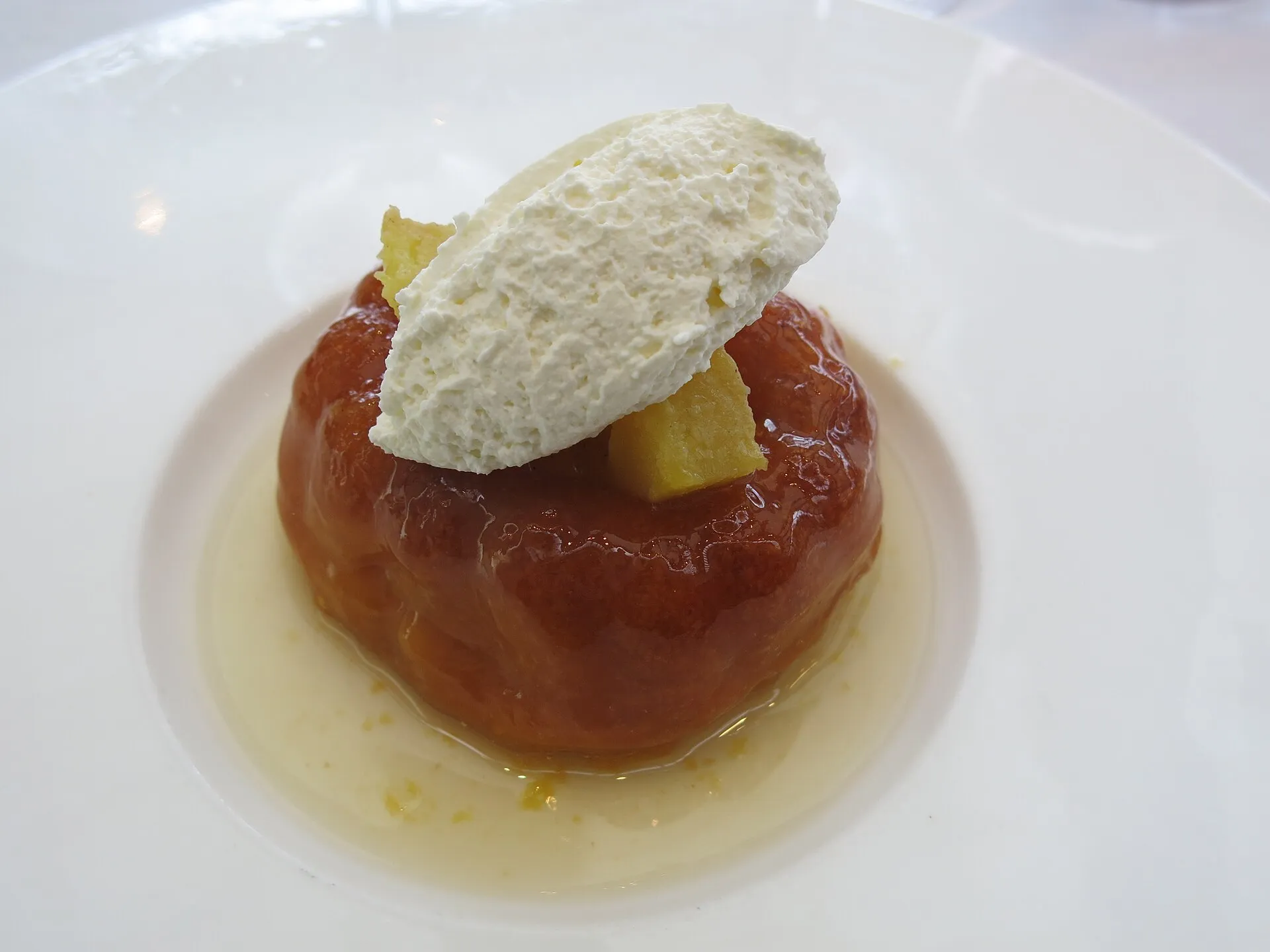 Baba au rhum nappé de sirop, coiffé de chantilly, servi sur une assiette en porcelaine