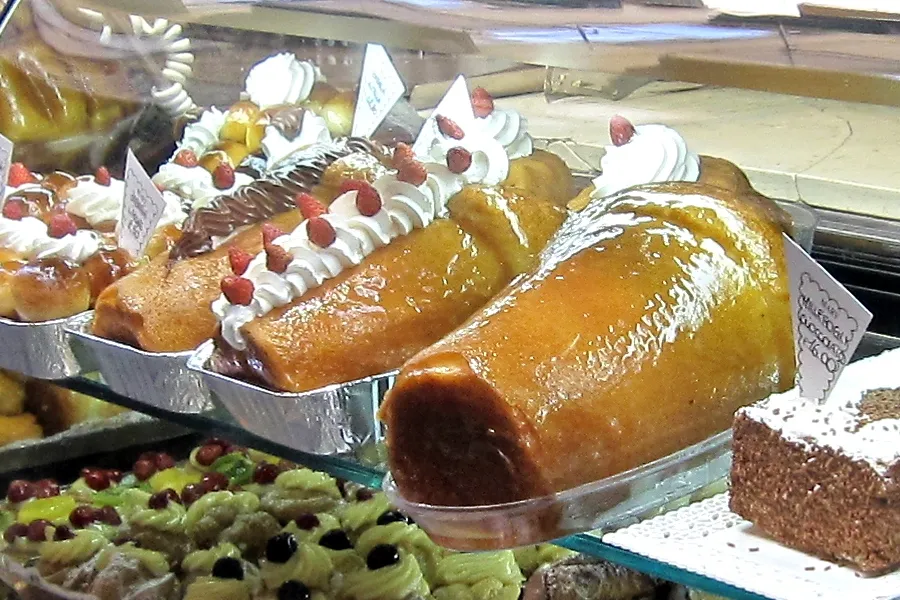 Vitrine d'une pasticceria napolitaine garnie de gros babàs dorés et luisants de sirop